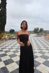 Vestido largo strapless de encaje negro con transparencias y espalda descubierta con tiras cruzadas, de corte entallado y falda de caída suelta.