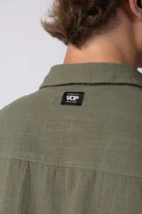 Camisa de hombre de manga corta color beige claro, confeccionada en lino. Tiene cuello clásico, cierre frontal con botones y corte recto.