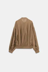 Camisa fluida de Zara Woman Collection, confeccionada en hilatura con mezcla de viscosa en tono tostado. Presenta cuello redondo, mangas largas con puños elásticos y diseño fruncido en la parte delantera. Dispone de cierre frontal con botones ocultos por solapa.