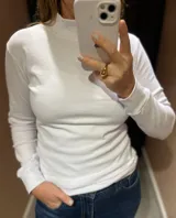 Polera de manga larga en color blanco, confeccionada en algodón, con cuello alto y ajuste al cuerpo.