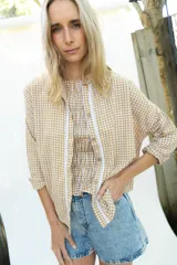 Camisa de manga larga con estampado vichy en color mostaza y blanco, cuello mao y apliques de encaje en la pechera. Diseño holgado con cierre frontal de botones y mangas con puños elásticos.