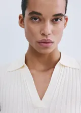 Chaleco de tejido de punto fino y diseño entallado, con cuello camisero, escote en V y mangas cortas.