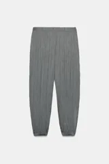 Pantalón de tiro medio con cintura elástica y bajo acabado en puño elástico. Presenta un diseño con tejido efecto arrugado y bolsillos laterales ocultos en costura.