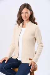 Campera tejida color beige, con cierre frontal, cuello alto y bolsillos laterales. Presenta una etiqueta de cuero sintético marrón en el dobladillo.