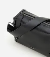 Cartera tipo shoulder de tamaño mediano, confeccionada en poliuretano con diseño rectangular. Presenta correas laterales decorativas con remaches metálicos, cierre superior con cremallera, herrajes en acabado gunmetal y correa larga ancha ajustable.