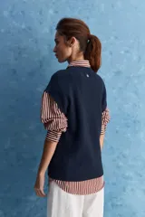 Chaleco de tejido de punto color beige claro, con cuello redondo y diseño de líneas limpias con hombros caídos y terminaciones acanaladas.