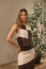 Musculosa de cuero ovino con diseño de bloques de color geométricos en beige y marrón oscuro. Presenta un acabado gastado artesanal y cierre metálico a lo largo de toda la espalda.