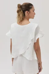 Blusa blanca de lino de manga corta, con volados en las mangas y espalda cruzada adornada con volados.