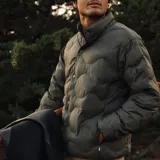 Campera puffer Katin color verde oliva, con diseño acolchado de ondas, cierre frontal con botones a presión y cuello alto.