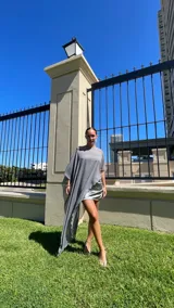 Vestido corto de satén con frunces laterales y acabado brillante, que incluye una capa desmontable de gasa transparente que se puede colocar de diversas formas.