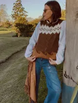 Chaleco tejido en mohair con diseño de guarda geométrica en la parte superior. Presenta una combinación de colores gris, blanco y beige, con cuello redondo y corte recto.