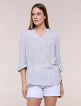Blusa de silueta relajada con textura tramada en color celeste. Presenta cuello mao abierto en V y mangas tres cuartos amplias con dobladillo ancho y pequeña abertura lateral en el puño.