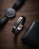 Pulsera de diseño masculino con banda central de acero inoxidable grabada con motivo de guarda griega y laterales de cuerina negra.