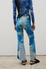 Pantalón de calce ajustado con diseño acampanado en el ruedo, confeccionado en tela sublimada con estampado artístico de bosque en tonos azules y celestes.