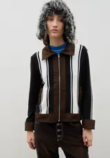 Campera de estilo casual confeccionada en una combinación de tejido de punto a rayas verticales en blanco y negro, con detalles en denim marrón en cuello, puños, ruedo y cierre frontal.