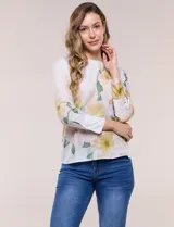 Blusa de silueta holgada y corte recto con caída fluida, escote redondo y mangas largas con puños anchos estructurados, con estampado floral en tonos pasteles sobre fondo blanco.