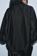 Camisa fluida de cuello redondo con escote en pico y lazada frontal en el mismo tejido. Presenta mangas largas con puños anchos y bajo recto.