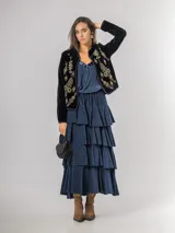 Falda midi de micro corderoy azul marino, con diseño de volados escalonados y cintura elástica. Presenta un corte asimétrico, siendo ligeramente más corta en la parte frontal.