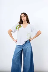 Remera amplia de algodón color blanco, con cuello en V, mangas cortas y estampa original en tono verde.