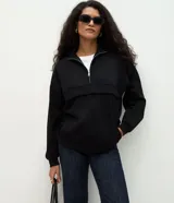 Buzo de modal color negro, con corte oversize, cuello alto con cierre frontal, mangas largas y recortes estructurados en el cuerpo.