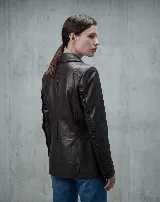 Blazer de cuero bovino color marrón oscuro, con silueta entallada, cuello sastre y detalles fruncidos a lo largo de las mangas. Cuenta con cierre frontal de botones y puños abotonados.