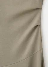 Vestido midi sin mangas color verde militar, con cuello alto envolvente y silueta evasé con costura diagonal en la falda.