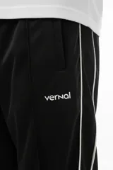 Pantalón de jogging negro con vivo lateral doble blanco, corte holgado, tiro medio, botamanga elastizada y cierres en los tobillos.