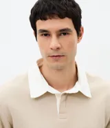 Buzo masculino de algodón con felpa, color beige, con cuello polo blanco contrastante, manga larga y puños acanalados.