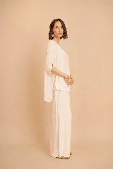 Conjunto de blusa amplia con mangas cortas y pantalón largo holgado, ambos en color beige.