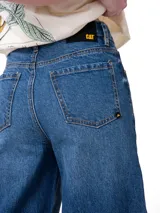 Jeans de corte wide leg en color azul medio, con diseño clásico de cinco bolsillos, cierre de cremallera y botón metálico. Presenta costuras en contraste y un calce holgado desde la cadera hasta el ruedo.