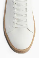 Championes blancos con collarín acolchado, lengüeta y cierre de cordones. Forro y plantillas en lona de algodón. Suelas texturizadas con diseño y grosor de 3,9 cm.