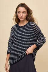 Sweater de tejido amplio en color azul marino con diseño de rayas horizontales y detalles calados. Cuenta con cuello redondo, mangas largas con hombros caídos y terminaciones acanaladas.