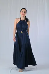 Vestido largo azul marino con cuello halter, corte imperio y falda acampanada. Presenta un cinturón con hebilla dorada a la altura de la cintura.