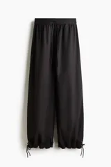Pantalón de popelina de algodón negro, de corte ancho y silueta globo con cordón ajustable en los bajos y en la cintura elástica.