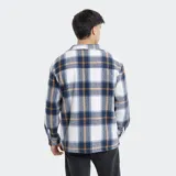 Camisa de franela a cuadros en tonos grises, blancos y negros, forrada con corderito sintético en el interior. Cuenta con mangas largas, bolsillos con solapa en el pecho y cierre frontal con botones.