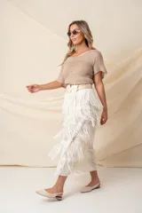 Pollera midi color vainilla, de gasa plisada con flecos y cintura elastizada.