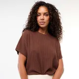 Sweater de punto calado color marrón, de mangas cortas y cuello redondo, con diseño holgado y detalle de nudo en el frente.