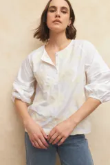 Blusa blanca de algodón bordada, de manga larga con cuello mao y mangas abullonadas con elástico en los puños.