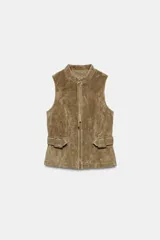 Chaleco de gamuza color marrón, con cuello alto, cierre frontal de cremallera y trabillas con hebilla a los lados de la cintura.