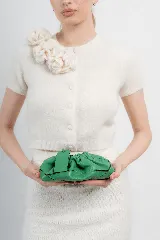 Cartera tipo sobre de cuero verde, con diseño fruncido y correa ajustable.