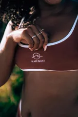 Conjunto de bikini color chocolate con ribete blanco, compuesto por un corpiño con breteles anchos y logo estampado y una bombacha de corte clásico.