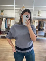 Sweater gris con cuello alto y mangas murciélago con detalle de banda negra en mangas y ruedo.