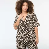 Blusa de punto crepé con estampado animal print tipo cebra en tonos marrón y crema. Presenta cuello solapa, cierre frontal con botones y mangas cortas de corte holgado.