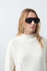 Polera de tejido de punto color marrón, con diseño asimétrico y costura diagonal frontal. Presenta cuello alto, hombros caídos, mangas largas con puños acanalados y ruedo con abertura frontal.