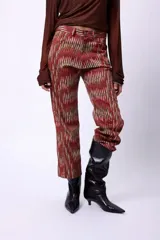 Pantalón de corte recto y largo al tobillo, con estampado de espiga en tonos oscuros y líneas rojas. Presenta tiro medio y cierre frontal.