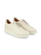 Sneakers de cuero napa color crema, de diseño minimalista y acordonado, con suela elevada y detalle metalizado en el talón.