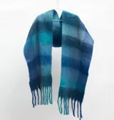 Bufanda amplia tipo mantón con diseño de cuadros en tonos azules y celestes, con flecos en los extremos.