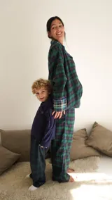 Conjunto de pijama a cuadros con ribetes en color lila, compuesto por camisa de manga larga con botones y pantalón largo.