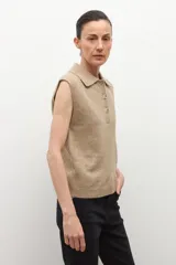 Chaleco de punto color tostado melange, con cuello polo y abotonadura frontal de tres botones. Sin mangas.