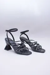 Sandalias de tacón geométrico con diseño de tiras finas lisas y trenzadas que se entrelazan en el empeine y tobillo. Cuentan con cierre de pulsera ajustable y punta cuadrada.